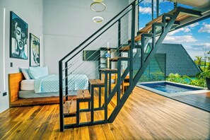 Un interior moderno con una escalera, una cama, una piscina pequeña y obras de arte en las paredes.