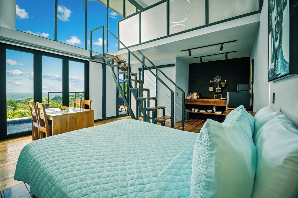 Une chambre moderne avec un grand lit, un coin repas et une vue sur l’extérieur.