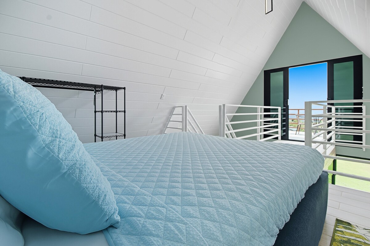 Un dormitorio con cama, una escalera y un balcón con vistas.