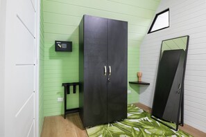 Une pièce avec une armoire noire, une petite étagère noire, un miroir et un tapis vert à motifs.