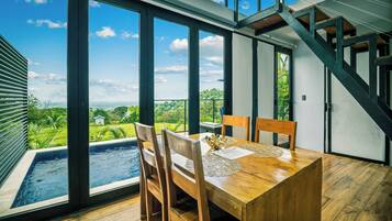 A dining area with a view of a swimming pool and greenery.