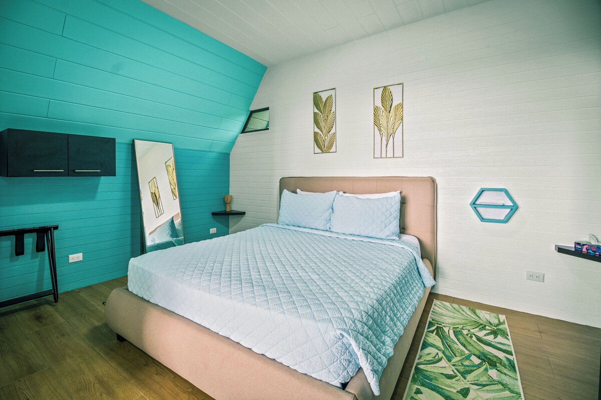 Un dormitorio con cama, mesita de noche, espejo y decoración en la pared.