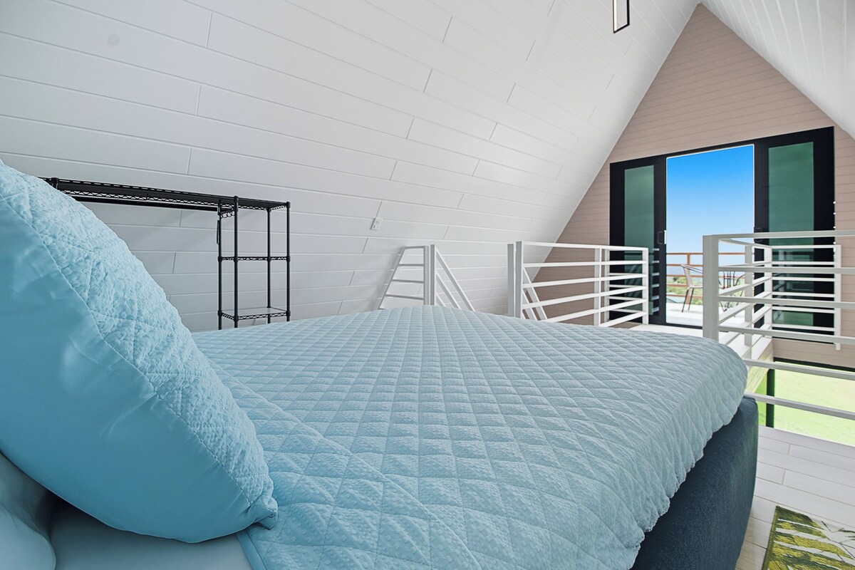 Un dormitorio con cama, escalera y balcón con barandilla.
