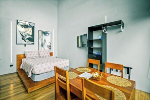 A modern bedroom with a bed, bedside tables, a desk with chairs, and artwork on the walls. - Junglo Resort And Spa (Peñas Blancas)