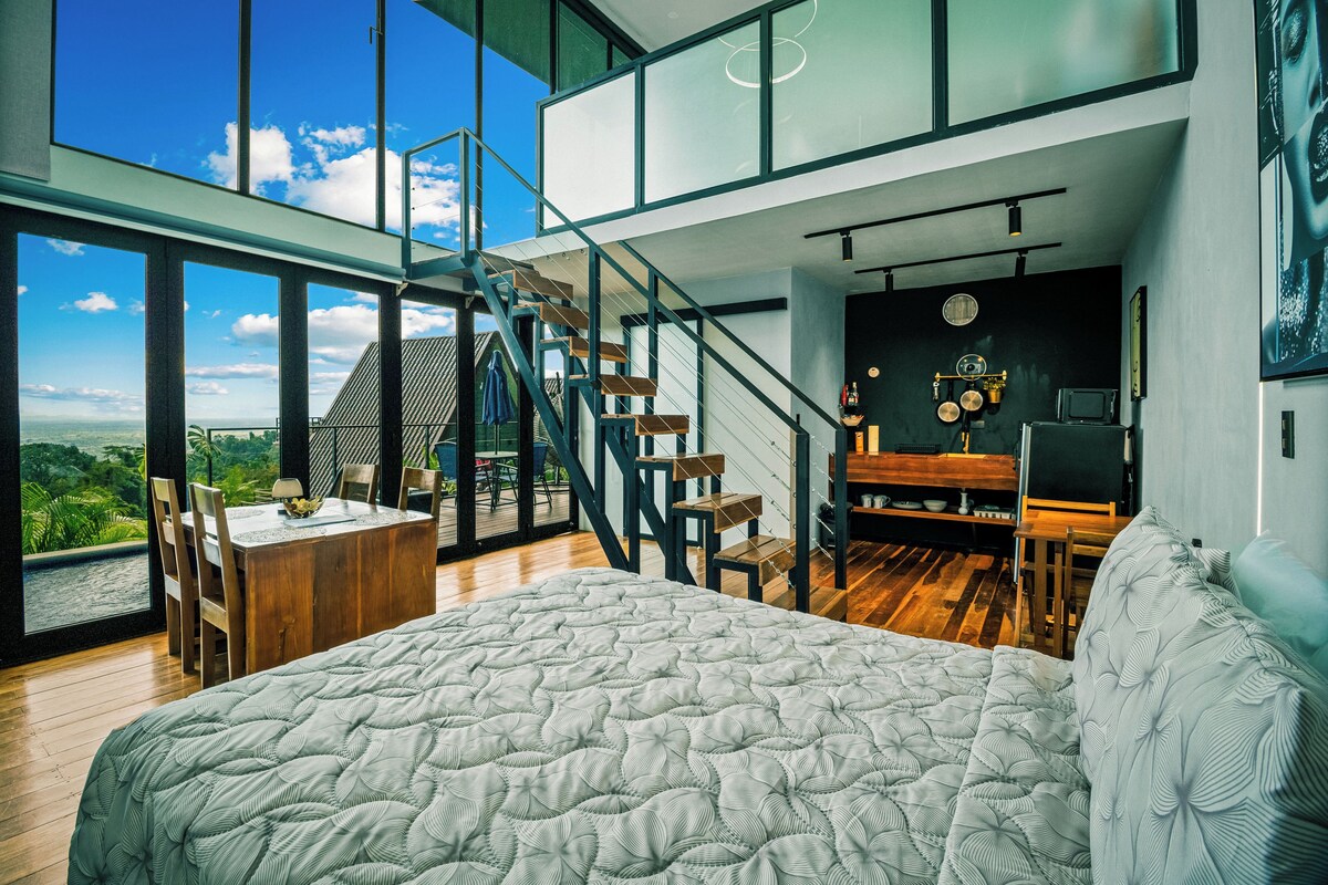 Une chambre moderne dotée d’un grand lit, d’un coin repas et d’un escalier menant à un niveau supérieur.