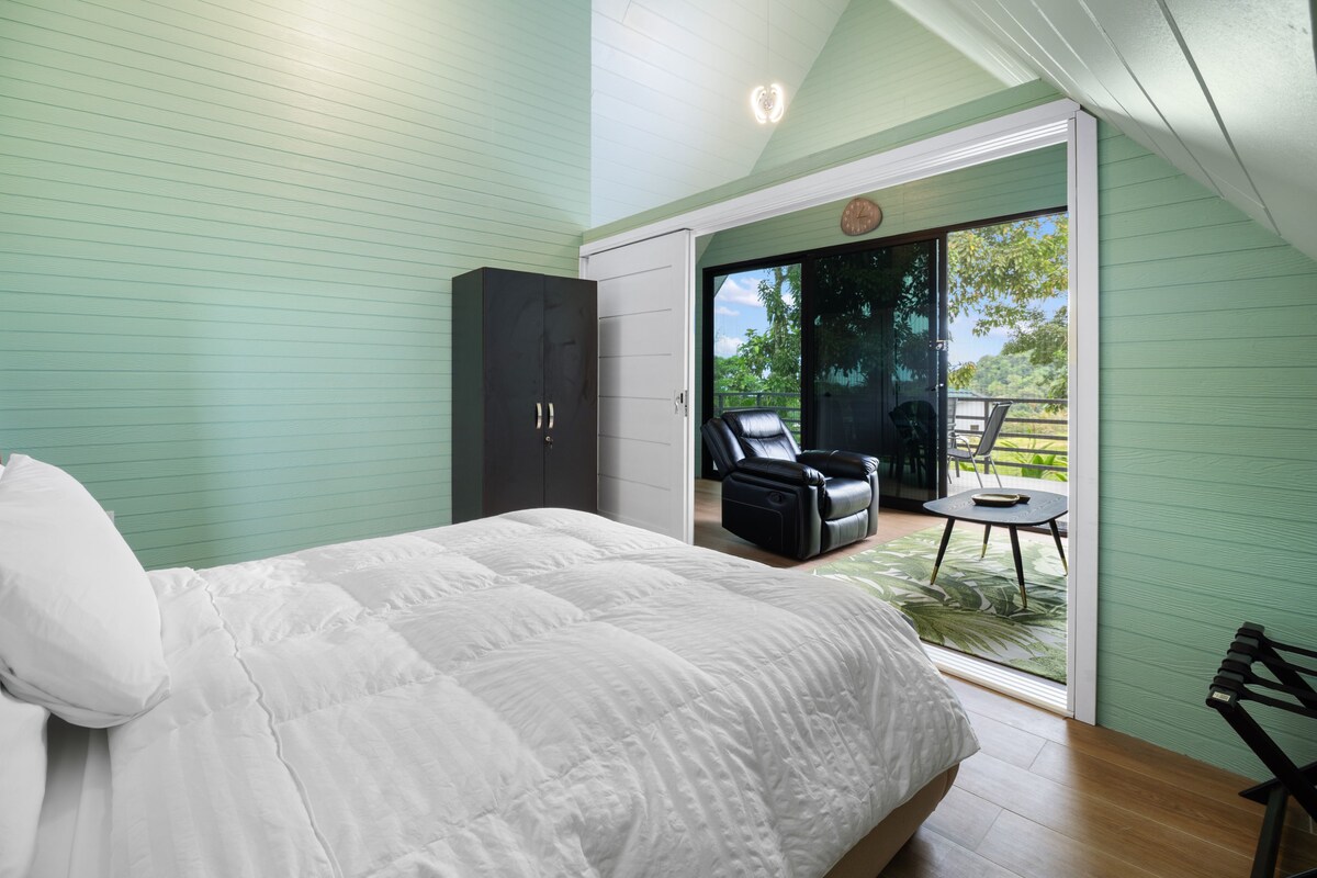 Un dormitorio con cama, armario y puerta corrediza de vidrio que da a un balcón con una silla y una mesa.