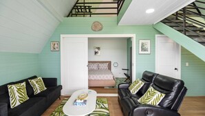 A compact living space with a bed, two sofas, a coffee table, and a staircase.