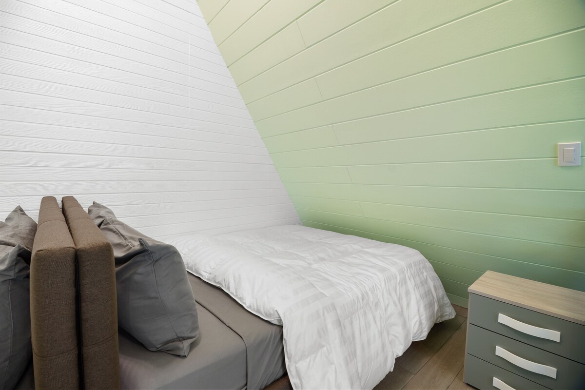 Un dormitorio con cama, almohadas, una mesita de noche y una cómoda.