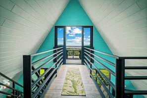A staircase leading to a balcony with a view of the sky and clouds.