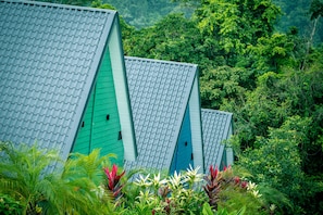 A row of green-roofed buildings surrounded by lush greenery. - Junglo Resort And Spa (Peñas Blancas)