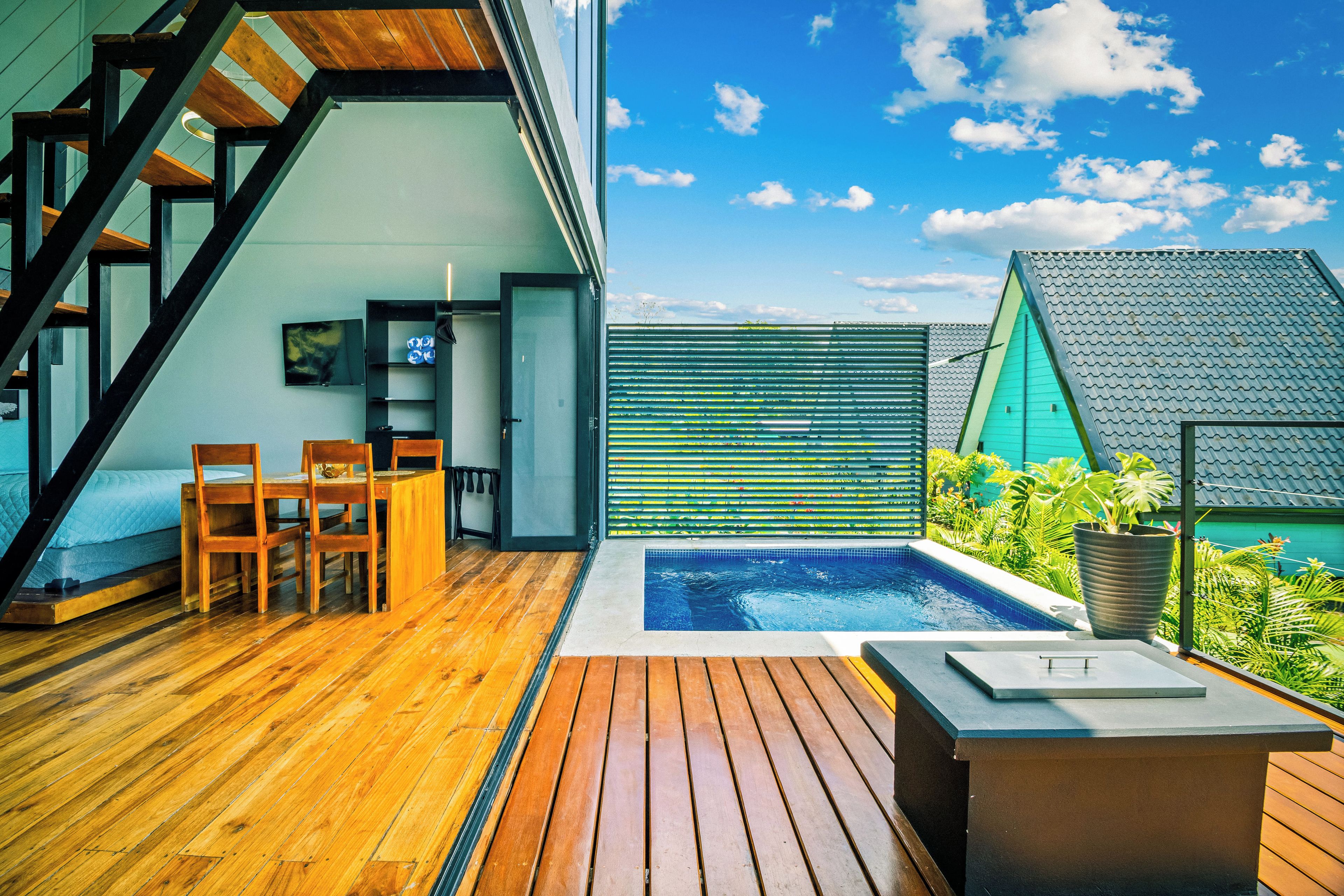 Une terrasse extérieure moderne avec un plancher en bois, une piscine et un espace salon avec des chaises.