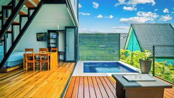 Une terrasse extérieure moderne avec un plancher en bois, une piscine et un espace salon avec des chaises.