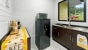 A kitchen with a black refrigerator, a sink, and a window with a view of greenery.