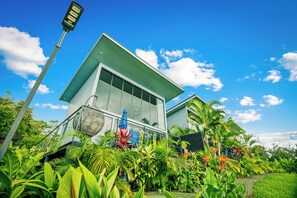 A modern house with a flat roof, large windows, and surrounded by lush tropical vegetation. - Junglo Resort And Spa (Peñas Blancas)