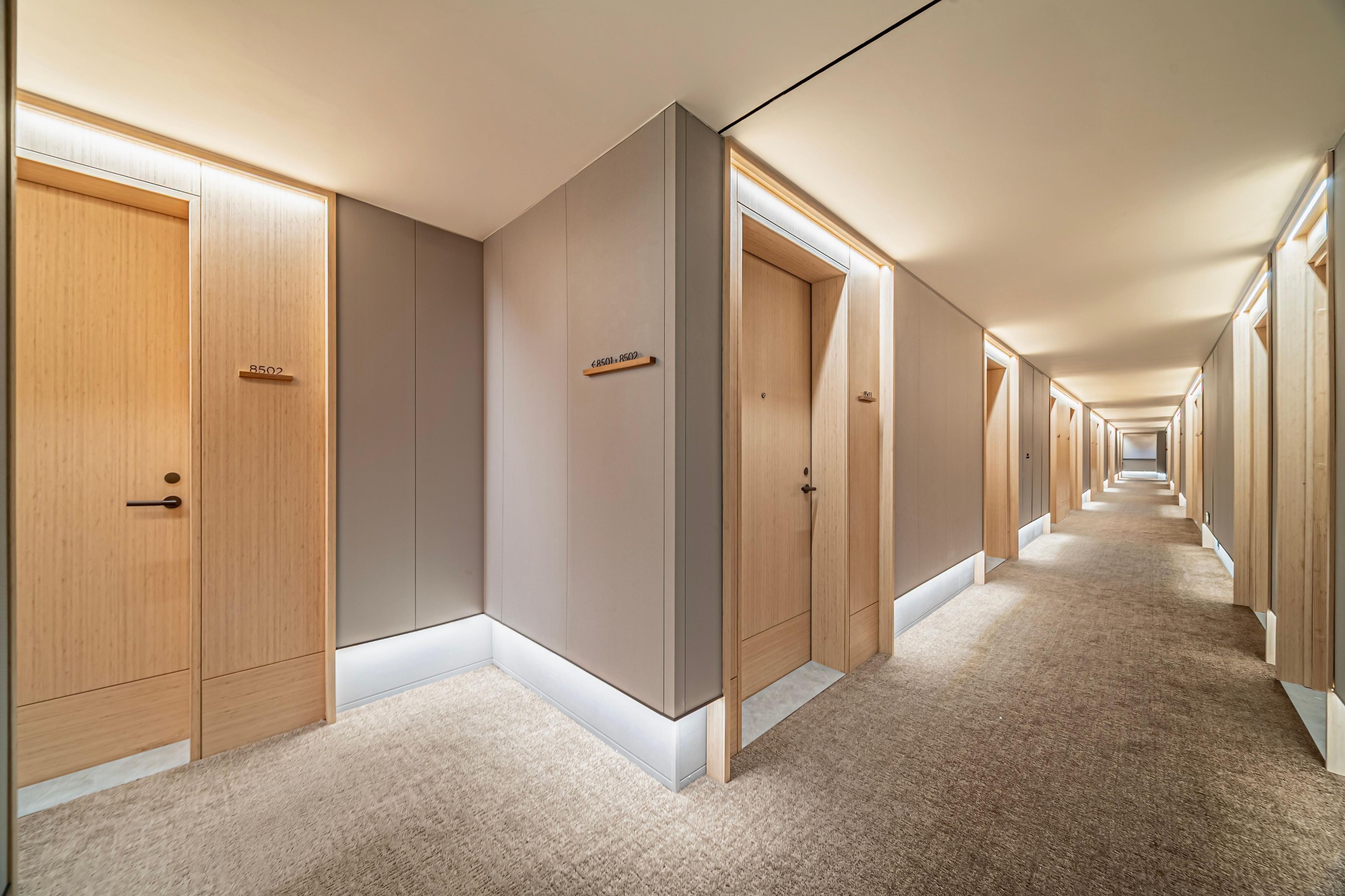 A long hallway with wooden doors and a carpeted floor.