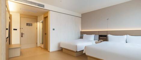 A hotel room with two beds, a desk, and a mirror.