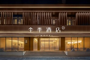 En hotellentrén med modern design, med en framträdande skylt med kinesiska tecken och ordet ”HOTEL” på engelska.