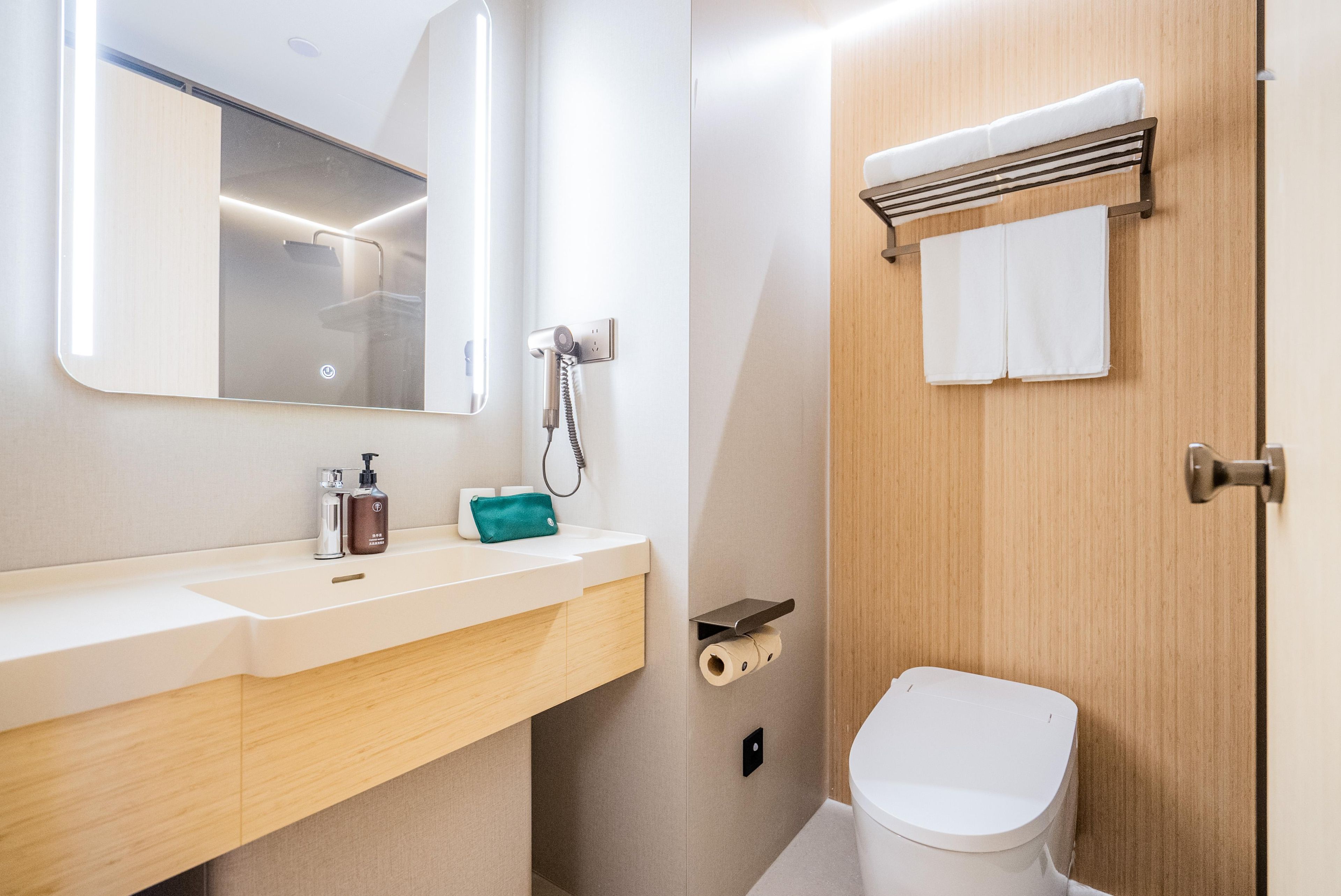 Une salle de bain moderne équipée d’un lavabo, d’un miroir, d’un porte-serviettes et de toilettes.