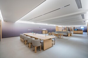 A spacious, modern conference room with a long table, several chairs, and a seating area with sofas and tables. - JI Hotel (Xi'an)