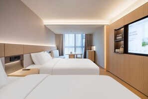 A hotel room with two beds, a desk, a TV, and a minibar. - JI Hotel (Xi'an)