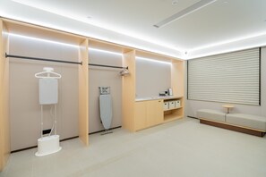 Una habitación moderna y bien iluminada con tocador, perchero y zona de estar con una mesa.