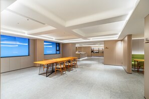 Una sala de conferencias moderna con una mesa larga, sillas y vistas al cielo a través de amplios ventanales.