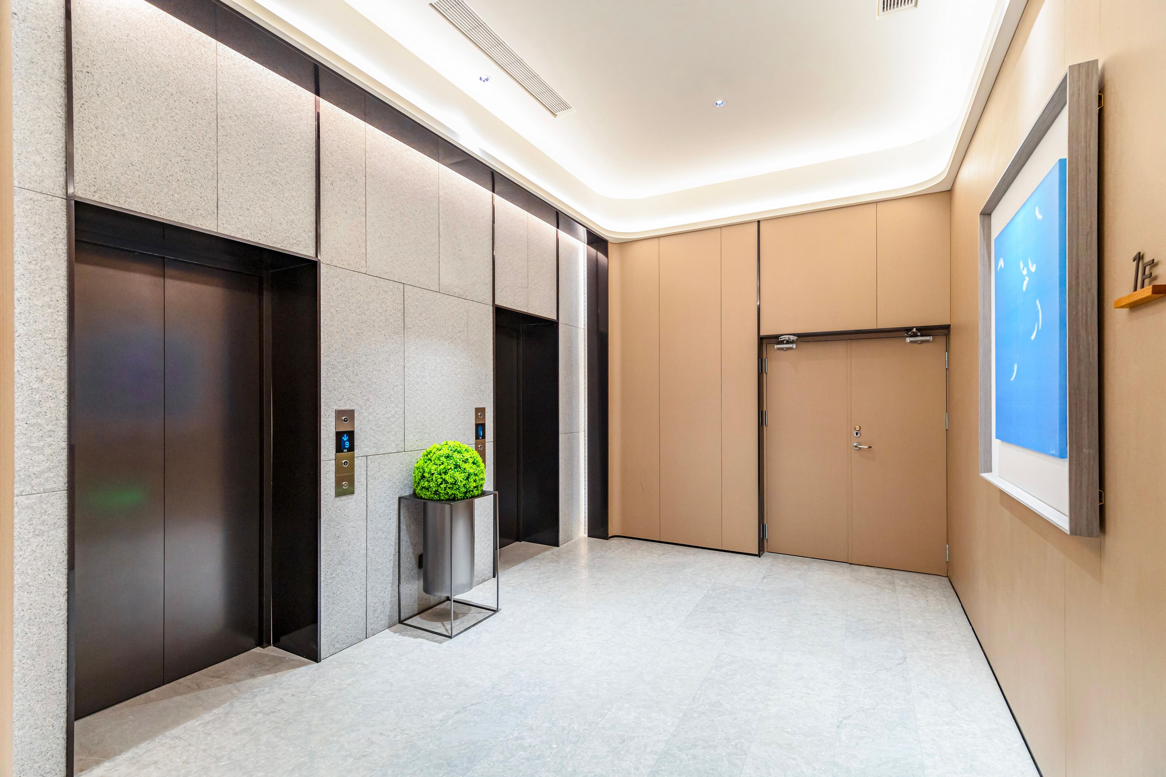 A modern elevator with a digital display, a small potted plant, and a wall-mounted sign.