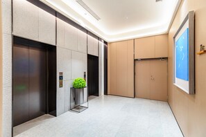 A modern elevator with a digital display, a small potted plant, and a wall-mounted sign. - JI Hotel (Xi'an)