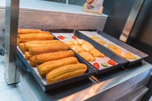 Presentación de alimentos con diversos pasteles y una bandeja de vegetales cortados.