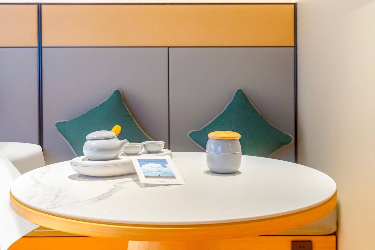 A round table with a white marble top, a tea set, a small bowl, and a photo card.