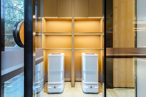 A modern elevator with a minimalist design, featuring two white, rectangular objects at the bottom, possibly air conditioning units, and a wooden panel wall with a horizontal light strip. - JI Hotel (Xi'an)