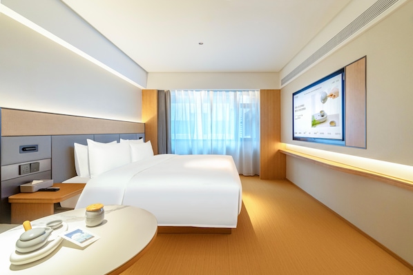 Habitación de hotel con cama, mesita de noche, televisor y ventana con cortinas.