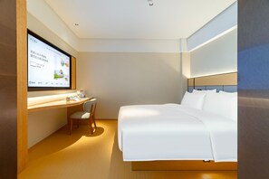 A hotel room with a bed, a desk, and a television screen displaying a welcome message. - JI Hotel (Xi'an)