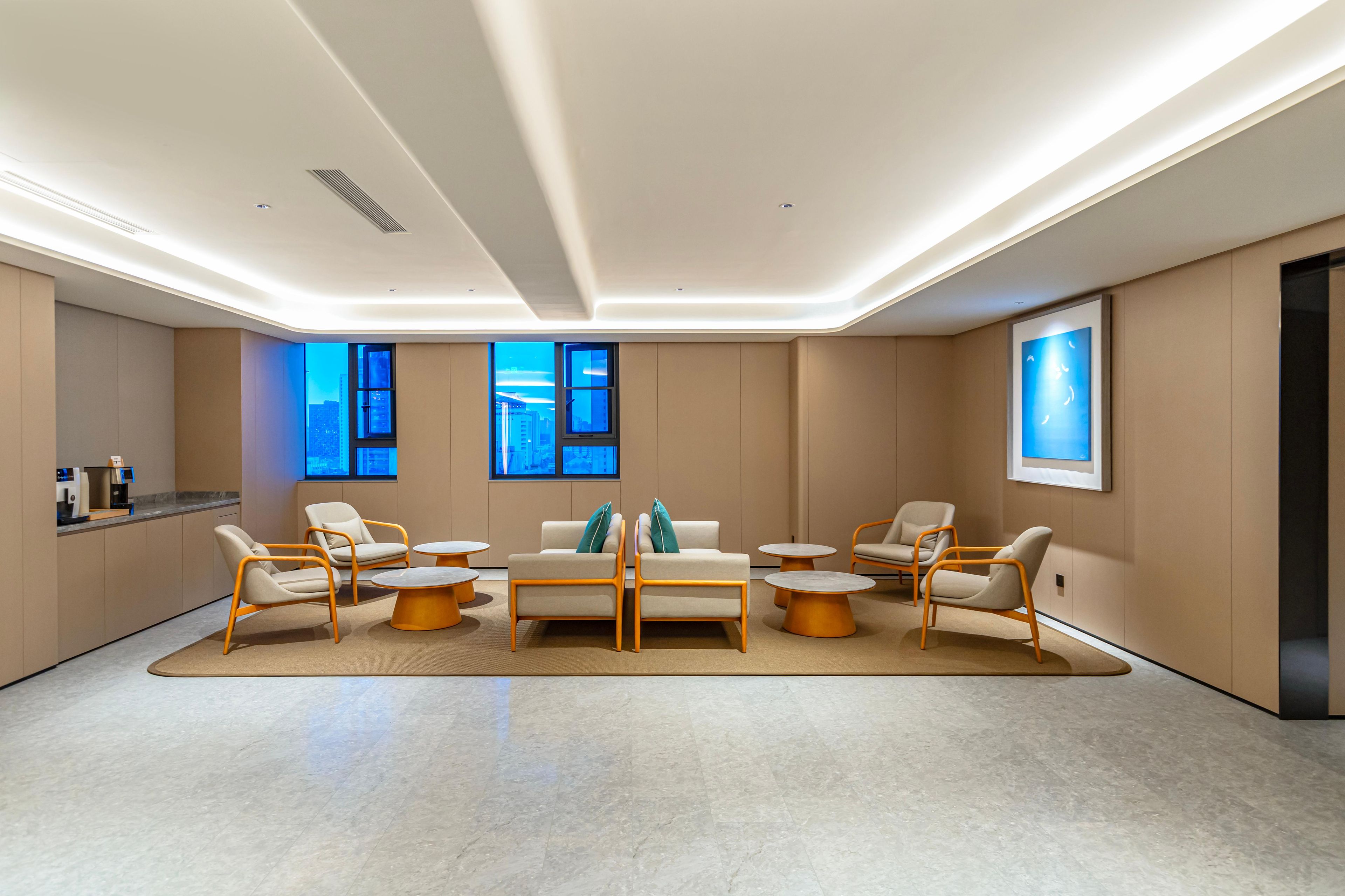Un hall d’hôtel moderne doté d’un espace salon central, de nombreuses fenêtres et d’un comptoir d’accueil.