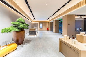 A modern hotel lobby with a reception desk, a large potted bonsai tree, and a clean, polished floor. - JI Hotel (Xi'an)