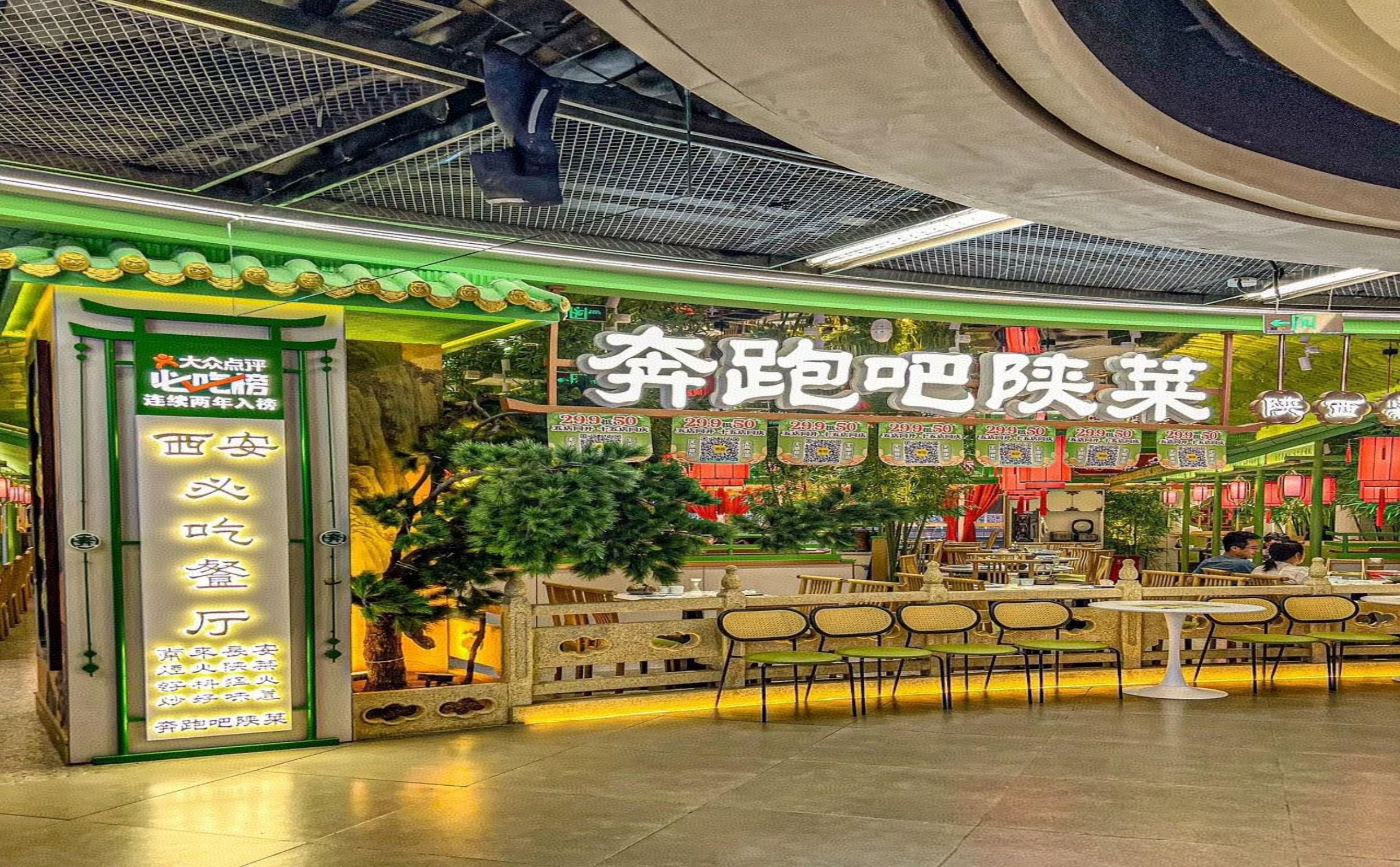 Ein Restaurant im Inneren, gestaltet im traditionellen chinesischen Architekturstil, mit einem grünen Vordach und einem Schild mit chinesischen Schriftzeichen.