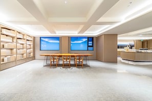 A spacious room with a long wooden table and chairs, a bookshelf, and large windows with a view. - JI Hotel (Xi'an)