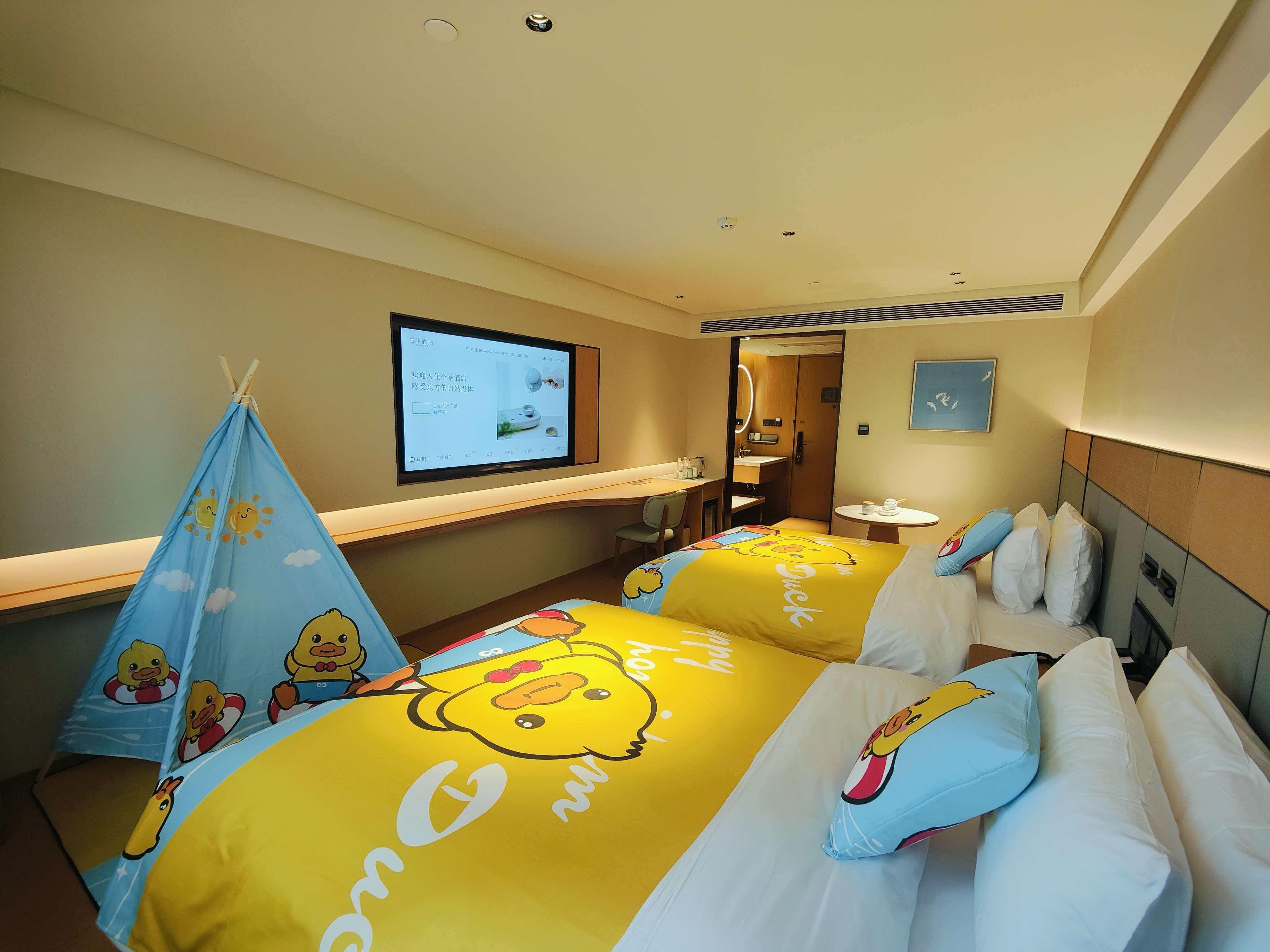 Une chambre d’hôtel avec deux lits, une télévision, un bureau et une salle de bain.