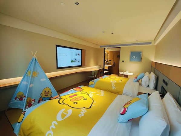 Habitación de hotel con dos camas, televisión, escritorio y baño.