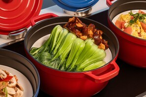 A red pot with bok choy and mushrooms on a table. - Meilun Hotel (Xi'an)