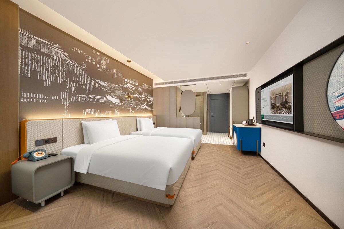 A hotel room with a large bed, bedside tables, a wall-mounted TV, and a modern design.