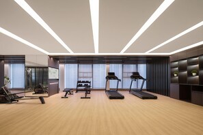 Ein modernes Fitnessstudio mit Laufbändern, Kraftgeräten und einer Spiegelwand.