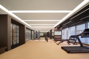 A modern gym with exercise equipment, a treadmill, and a mirrored wall. - Meilun Hotel (Xi'an)