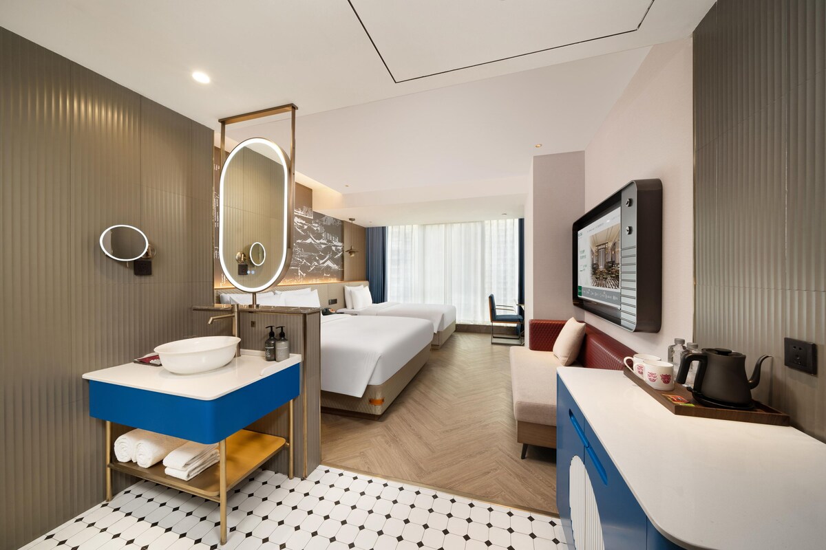 A hotel room with a bathroom, a bed, a desk, and a television.