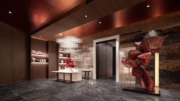 Un vestíbulo moderno con piso de mármol, un mostrador de recepción central y una escultura roja única.