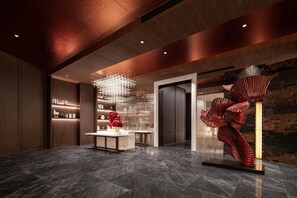 A modern lobby with a marble floor, a central reception desk, and a unique red sculpture. - Meilun Hotel (Xi'an)