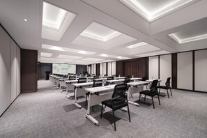 Une salle de conférence équipée de plusieurs tables et chaises, d’un pupitre et d’un écran de présentation.