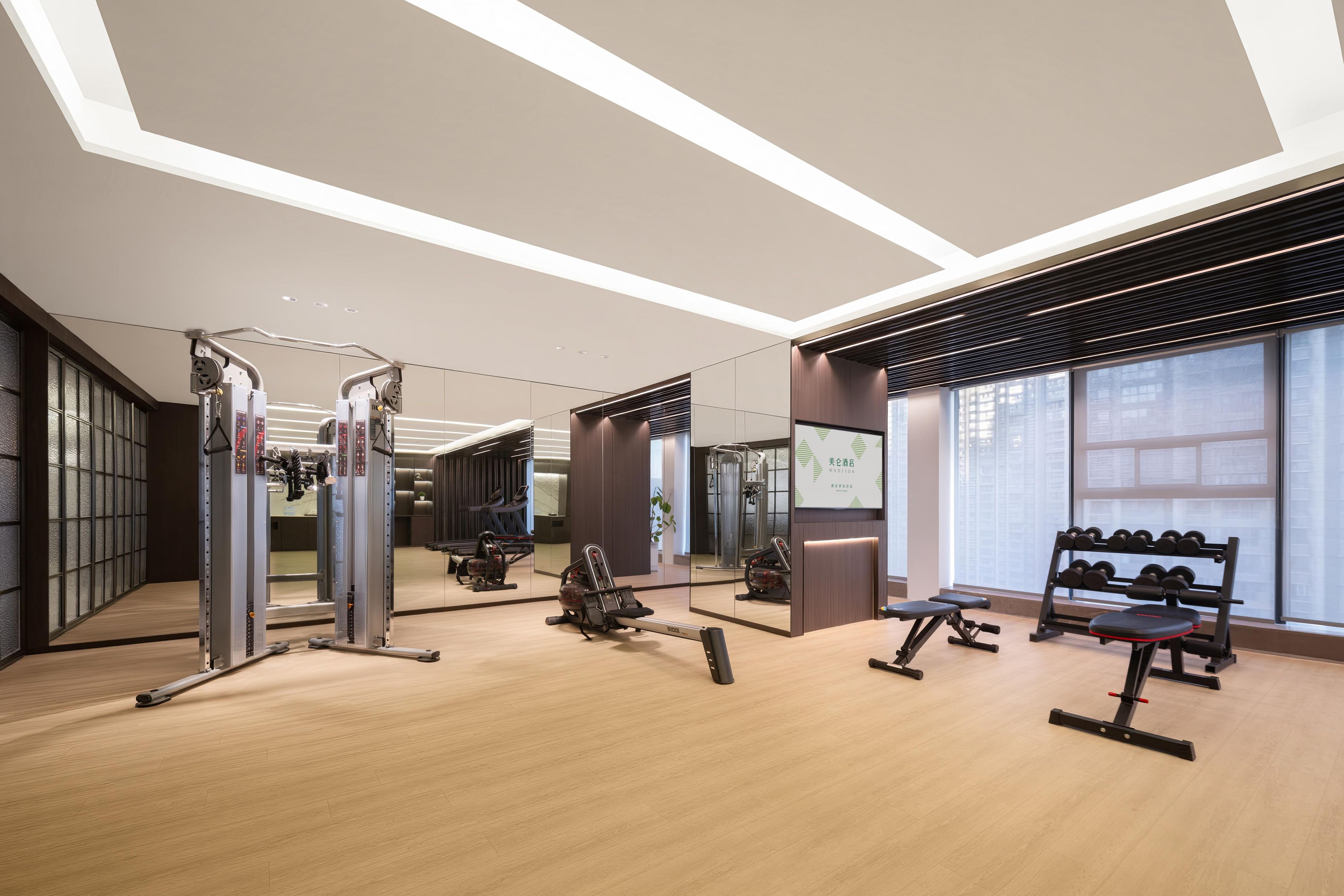 A modern gym with various exercise equipment, large windows, and a clean, minimalist design.