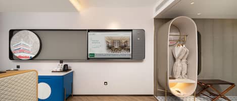 A modern hotel room with a large digital screen displaying a restaurant menu, a blue and white cabinet, a wooden floor, and a unique circular seating area.