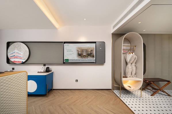 A modern hotel room with a large digital screen displaying a restaurant menu, a blue and white cabinet, a wooden floor, and a unique circular seating area. - Meilun Hotel (Xi'an)
